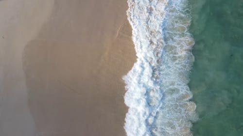 A Drone Footage of Beach Waves Crashing on Sand