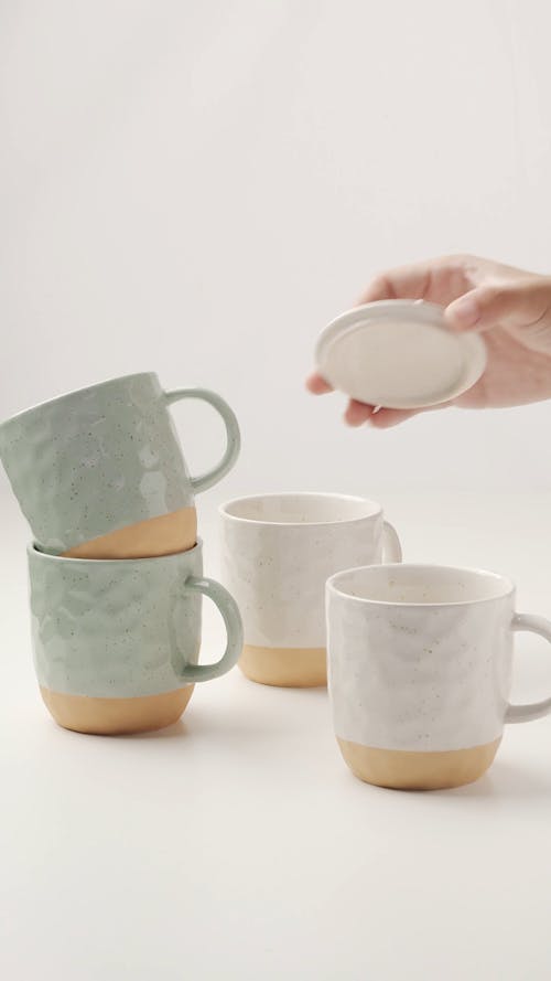 A Person Placing a Lid on a Ceramic Mug 