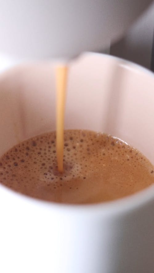 Close up of an Espresso Machine Pouring Coffee into a Ceramic Cup