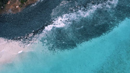 Top View of a Beach with Black Volcanic Rocks and Turquoise Water