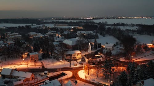 An Aerial Footage of Houses on a Snow Covered Ground with Trees at Night