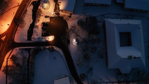 An Aerial Footage of Moving Cars on the Road Near the Houses on a Snow Covered Ground