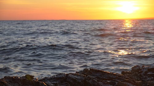 A Rocky Shore under an Orange Sunrise Sky 