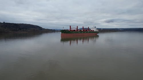 A Cargo Ship Anchored in a River under a Cloudy Sky