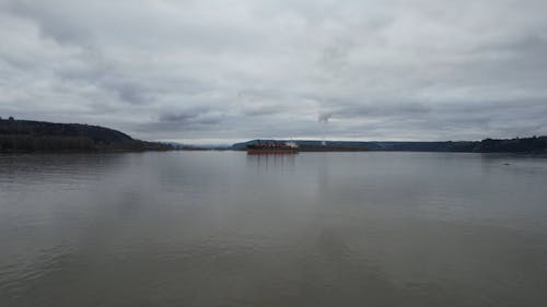 Drone Footage of a Cargo Ship Anchored in a River under a Cloudy Sky