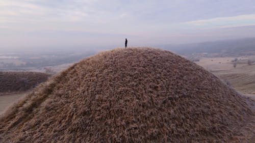 An Aerial Footage of a Man Standing on Top of the Hill