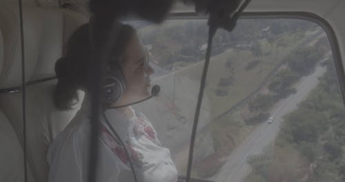 Woman Wearing a Headphones While Sitting on a Helicopter 