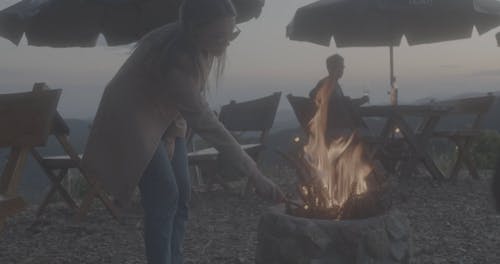Blonde Woman Playing With Campfire While her Lover is Watching