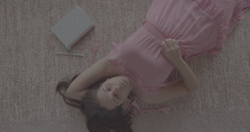 A Woman Lying on The Carpet While Thinking 