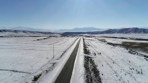 Drone Footage of an Asphalt Road and Snow Covered Land