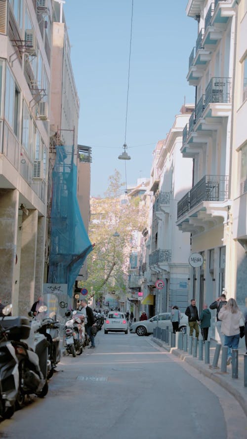 People Walking on Sidewalk in a Narrow Street