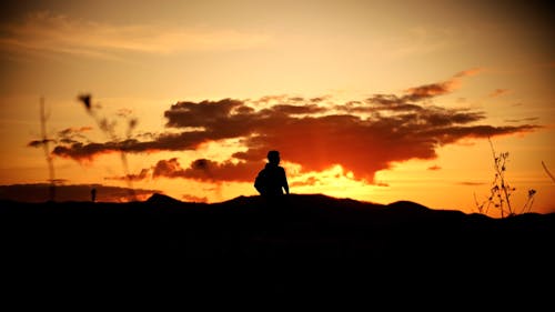 Silhouette of a Man Standing against a Dramatic Sunset Sky 