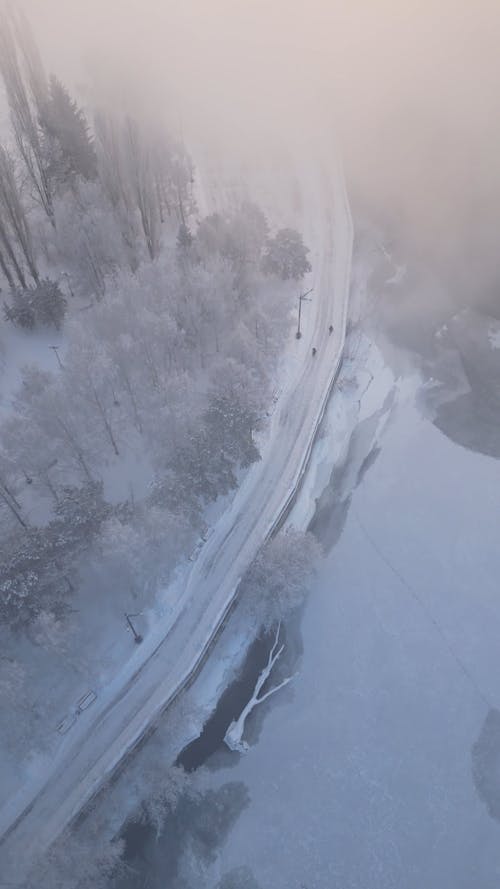 A Drone Footage of a Frozen Creek Between Snow Covered Ground