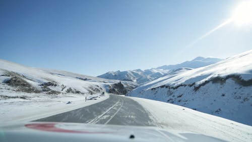 A Moving Cars on the Road Between Snow Covered Mountains