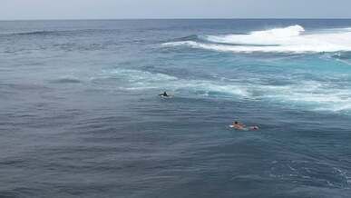 an aerial footage of people swimming on the sea with big waves