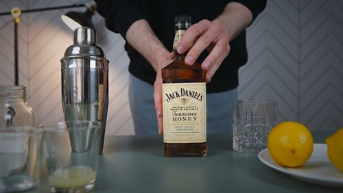 Person Sliding a Bottle of Whisky on the Table