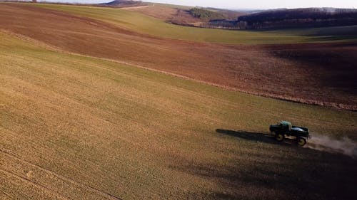 Drone Footage of a Tractor Driving across a Vast Field 