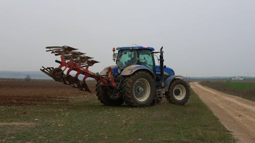 A Farmer Using a Tractor to Plough a Field 