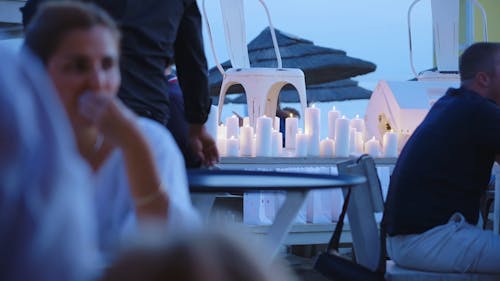 Empty chair surrounded by candles on a busy outdoors restaurant