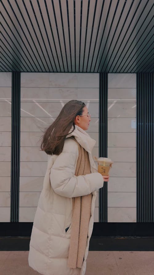 A Woman at a Metro Station Holding an Iced Coffee Plastic Cup 