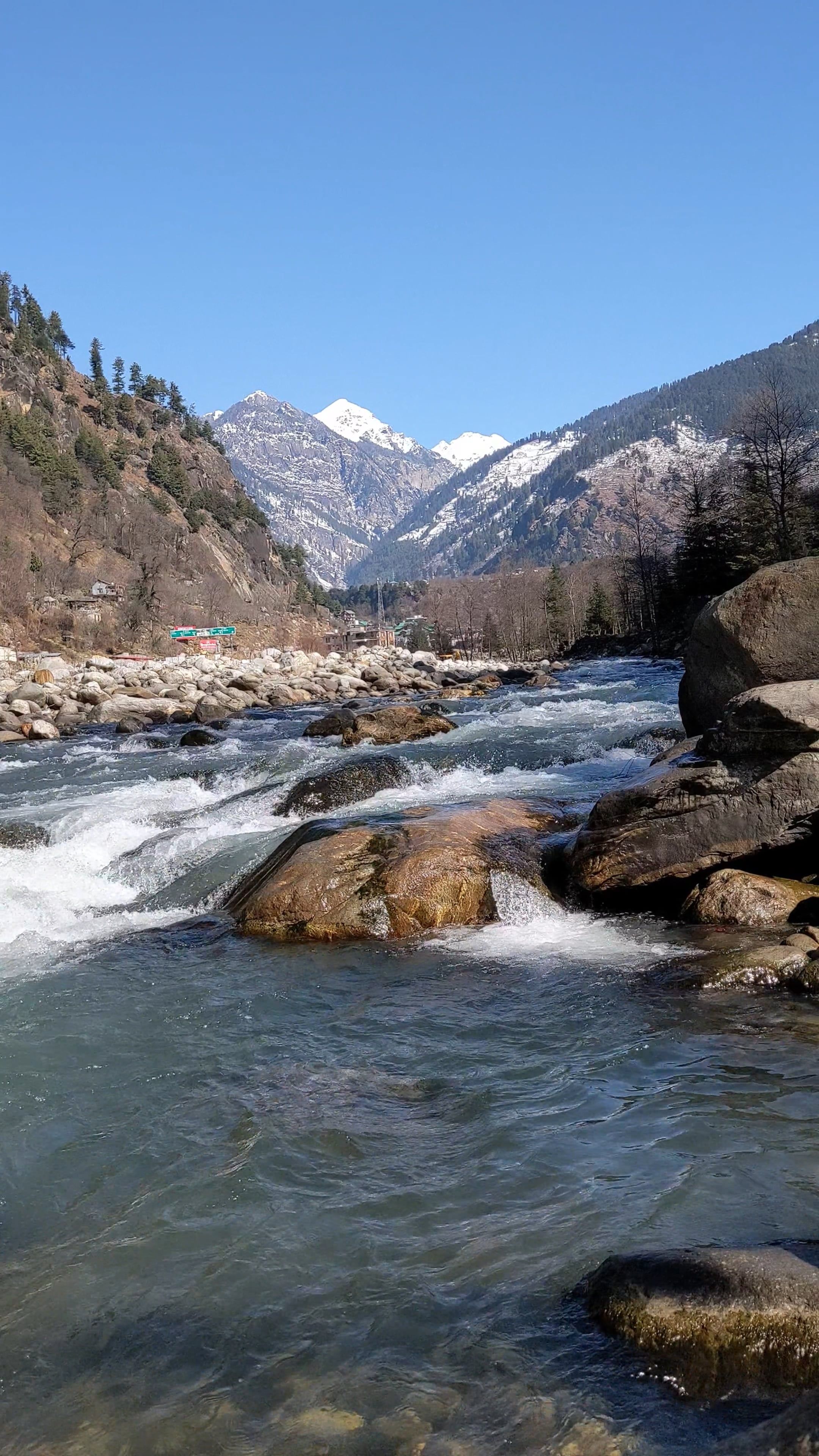 A river flowing through a rocky area with mountains in the background ...