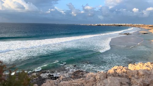 Breaking Waves on the Beach under a Cloudy Sky 