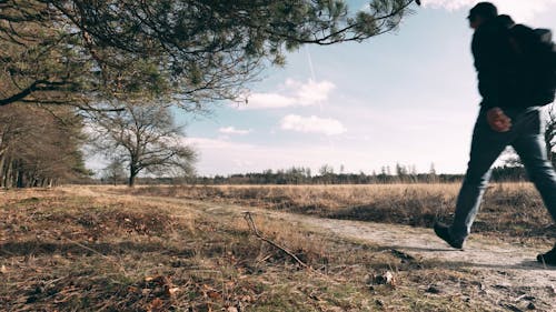 A Hiker Walking along a Dirt Path in the Countryside 