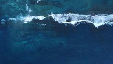 top view of breaking waves in the blue sea