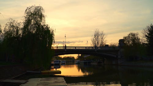 Silhouettes of Pedestrians and Vehicles Crossing a Bridge at Sunset