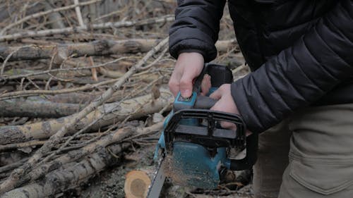 A Person Using a Chainsaw to Cut a Wood Log