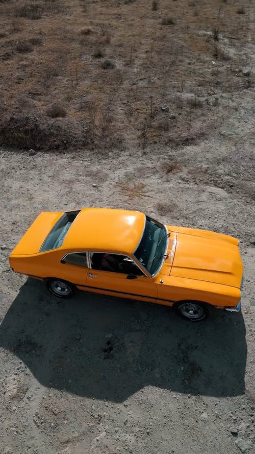 Drone Video of a Yellow Ford Maverick on a Road in the Countryside 