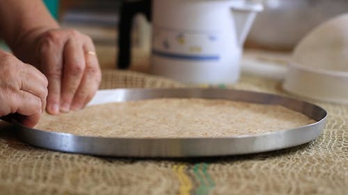 Close up of a Person Spreading Dough on a Baking Tray