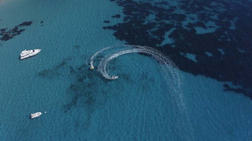 A Water Scooter Towing an Inflatable Boat on Turquoise Sea Waters 