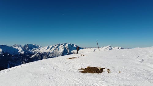 A Man Walking on a Snow Covered Hill under a Blue Sky