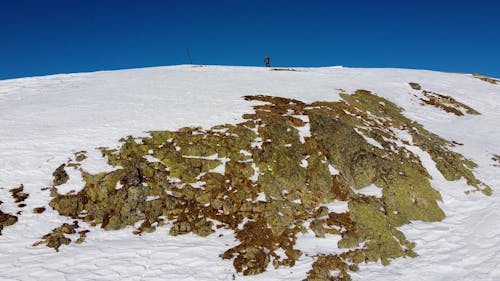 A Man Walking at the Top of a Snow Covered Hill