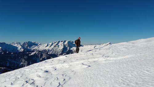 Drone Video of a Man Walking on a Snow Covered Hill