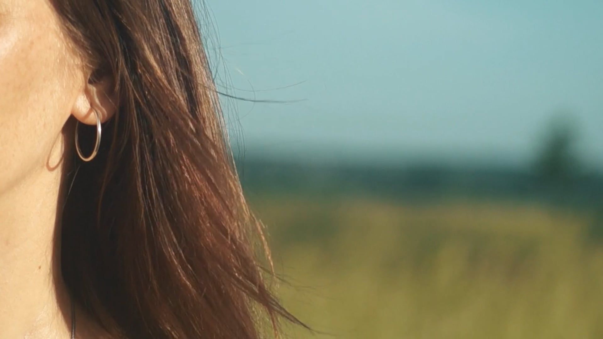A woman with long hair and earrings standing in a field Free Stock ...