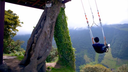 Teenager enjoys the Swing at the end of the world in Baños, Ecuador