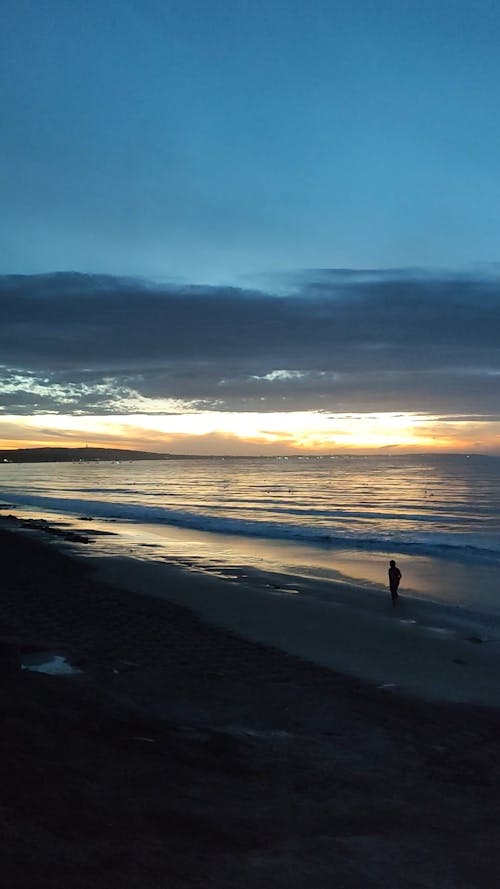 Silhouettes of Two People Walking on the Beach at Sunrise 