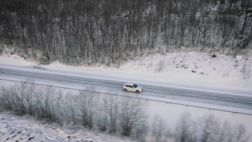 A Car Driving along an Empty Road in a Winter Landscape 