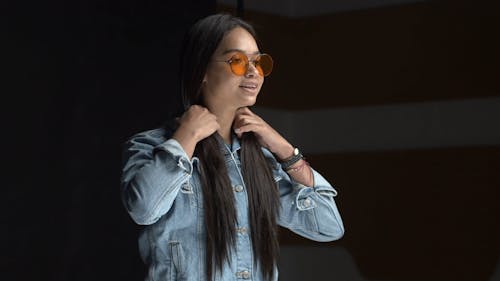 A Young Woman in a Denim Jacket and Tinted Sunglasses Posing during a Photo Session 