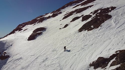 Drone Video of a Man Climbing a Snow Covered Mountain 