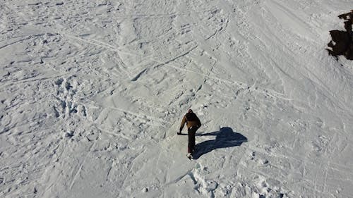 Drone View of a Man Climbing a Snow Covered Mountain