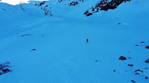 Drone Footage of a Man Walking on a Snow Covered Mountain 
