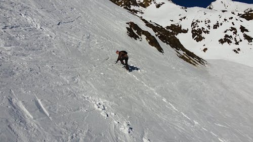 Drone Footage of a Man Climbing a Snow Covered Mountain