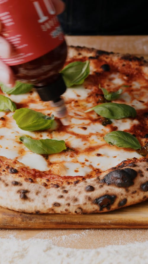 A Person Adding Hot Honey to a Sourdough Pizza Margherita