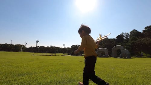  A Little Boy Running in the Park with a Toy Airplane 