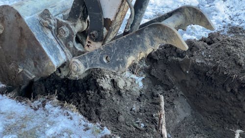 Close up of an Excavator Digging on Snow Covered Ground