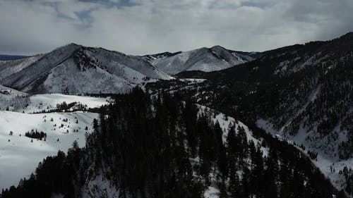 A Snowy Mountain Landscape under a Cloudy Sky 