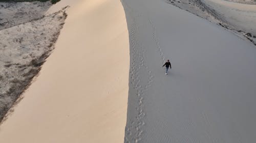 Drone Video of a Man Walking on a Sand Dune 